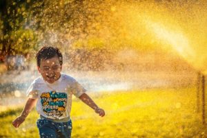 child running in sprinkler