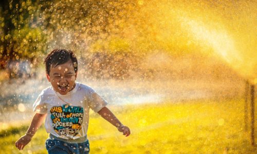 child running in sprinkler